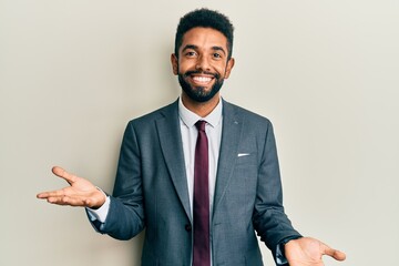 Handsome hispanic man with beard wearing business suit and tie smiling cheerful with open arms as friendly welcome, positive and confident greetings