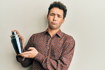 Young handsome man preparing cocktail mixing drink with shaker depressed and worry for distress, crying angry and afraid. sad expression.