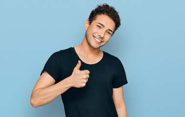Young handsome man wearing casual black t shirt doing happy thumbs up gesture with hand. approving expression looking at the camera showing success.