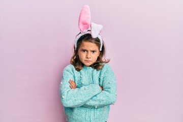 Little beautiful girl wearing cute easter bunny ears skeptic and nervous, disapproving expression on face with crossed arms. negative person.