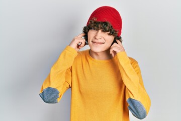 Handsome young man wearing wool hat covering ears with fingers with annoyed expression for the noise of loud music. deaf concept.