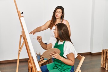 Student and teacher with serious expression painting at art school.