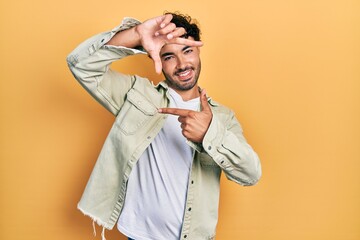 Young hispanic man wearing casual clothes smiling making frame with hands and fingers with happy face. creativity and photography concept.