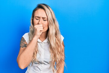 Beautiful young blonde woman wearing casual white shirt feeling unwell and coughing as symptom for...