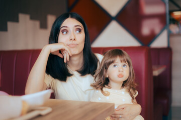 Stressed Mom Sitting with her Child in a Restaurant Booth