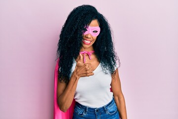 Middle age african american woman wearing super hero costume doing happy thumbs up gesture with hand. approving expression looking at the camera showing success.