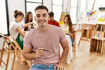 Group of people drawing sitting on the table. Young man smiling happy looking to the camera at art studio.