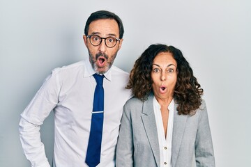 Middle age couple of hispanic woman and man wearing business office uniform afraid and shocked with surprise expression, fear and excited face.