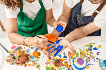 Two middle age student smiling happy painting hands at art studio.