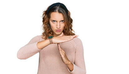Beautiful young caucasian woman wearing casual sweater doing time out gesture with hands,...