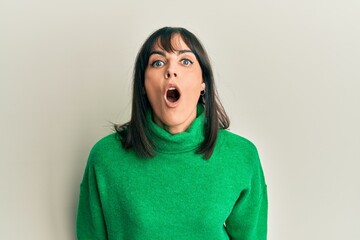 Young hispanic woman wearing casual winter sweater scared and amazed with open mouth for surprise, disbelief face