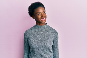 Young african american girl wearing casual clothes looking away to side with smile on face, natural expression. laughing confident.