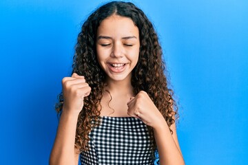 Teenager hispanic girl wearing casual clothes celebrating surprised and amazed for success with arms raised and eyes closed