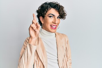 Young man wearing woman make up and woman clothes smiling with an idea or question pointing finger...