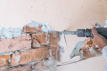 Worker use demolition hammer drill to break up wall surface. Motion blur intended.