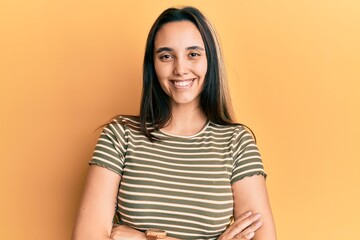 Obraz premium Young hispanic woman wearing casual striped t shirt happy face smiling with crossed arms looking at the camera. positive person.