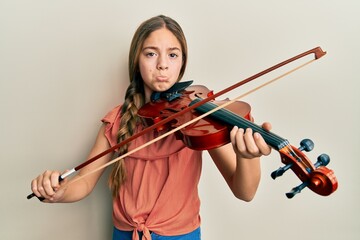 Beautiful brunette little girl playing violin depressed and worry for distress, crying angry and...