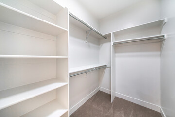 Small walk in closet with white shelvings and rods