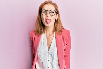 Young caucasian woman wearing business style and glasses sticking tongue out happy with funny...