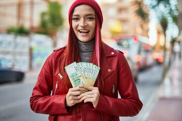 Young caucasian girl smiling happy holding russian ruble banknotes at the city.
