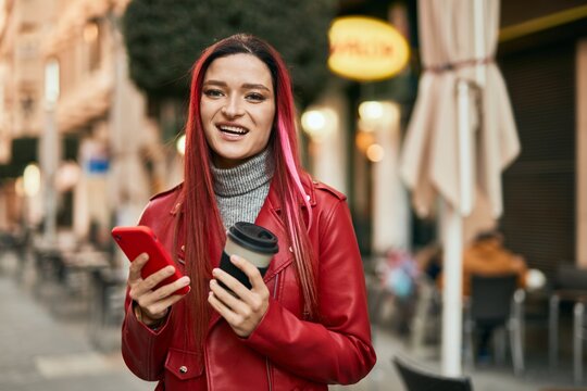 Young caucasian girl smiling happy using smartphone and drinking coffee at the city.