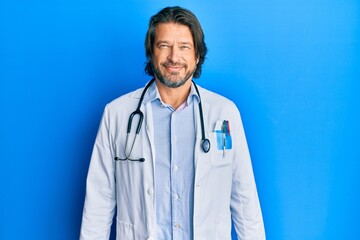 Middle age handsome man wearing doctor uniform and stethoscope with a happy and cool smile on face. lucky person.