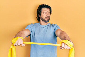 Middle age caucasian man wearing sportswear and arm elastic band clueless and confused expression....