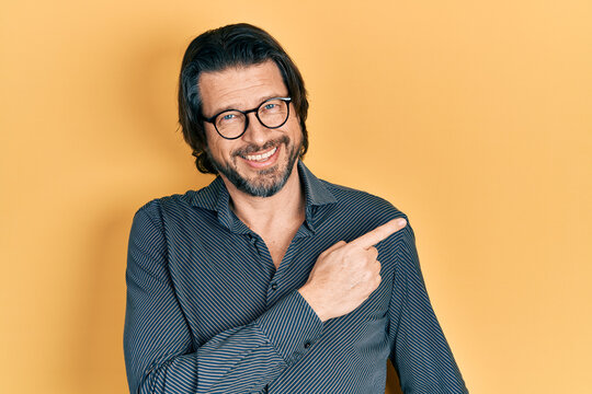 Middle age caucasian man wearing casual clothes and glasses smiling cheerful pointing with hand and finger up to the side