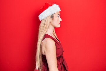 Young blonde girl wearing christmas hat looking to side, relax profile pose with natural face with confident smile.