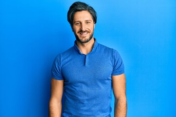 Young hispanic man wearing casual blue t shirt with a happy and cool smile on face. lucky person.