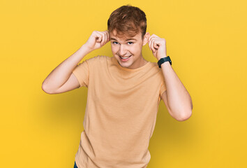 Young caucasian man wearing casual clothes smiling pulling ears with fingers, funny gesture....