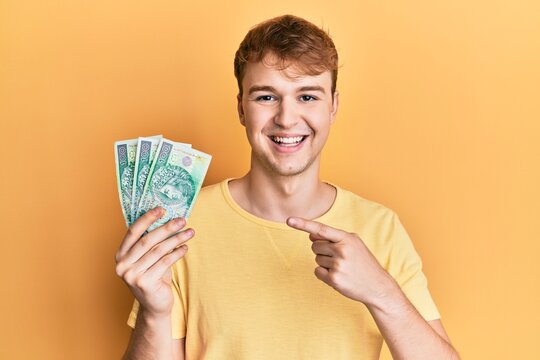 Young Caucasian Man Holding 50 Polish Zloty Banknotes Smiling Happy Pointing With Hand And Finger