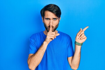 Young hispanic man wearing casual clothes asking to be quiet with finger on lips pointing with hand to the side. silence and secret concept.