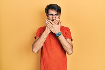 Young hispanic man wearing casual clothes and glasses shocked covering mouth with hands for mistake. secret concept.