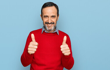 Middle age hispanic man wearing casual clothes success sign doing positive gesture with hand, thumbs up smiling and happy. cheerful expression and winner gesture.