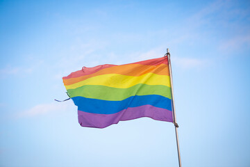 Gay pride flag photographed with blue sky in background