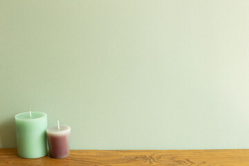 Color candles on wooden table. green wall background. home interior