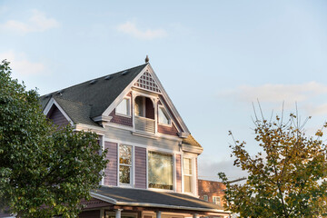 Part of a two storey traditional cottage house with an attic balcony and a bird on top of the roof