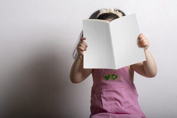 Girl holding a children storybook with a blank cover in front of her face - editable mockup template