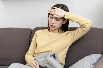 Upset woman feels a migraine headache or depression or sick. Disappointed Asian woman touches her forehead and has a high fever.