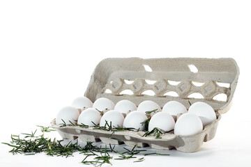 Bucket of 12 white eggs on a white background with fresh rosemary leaves.