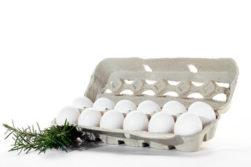 Bucket of 12 white eggs on a white background with fresh rosemary branches