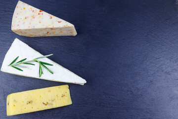 Set of various types of cheese on black slate background. Top view