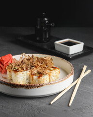 Tuna sushi in white dish served with soy and wasabi sauce, pickled ginger. Sushi set with tuna shavings on top.