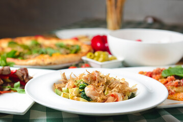 Spaghetti with shrimps, tuna shavings, and vegetables - zucchini, cucumbers, avocado.