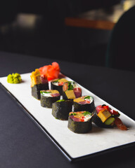 Maki Sushi set on a white plate over black background. Japanese cuisine concept, maki rolls.