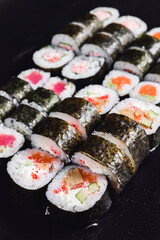 Mix of Japanese nori rolls in on a black background. Traditional Japanese sushi set over black.