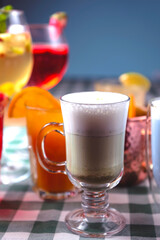 Set of alcoholic cocktails in raw on a wooden table with green plaid tablecloth.