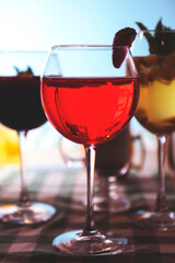 Set of alcoholic cocktails in raw on a wooden table with green plaid tablecloth.