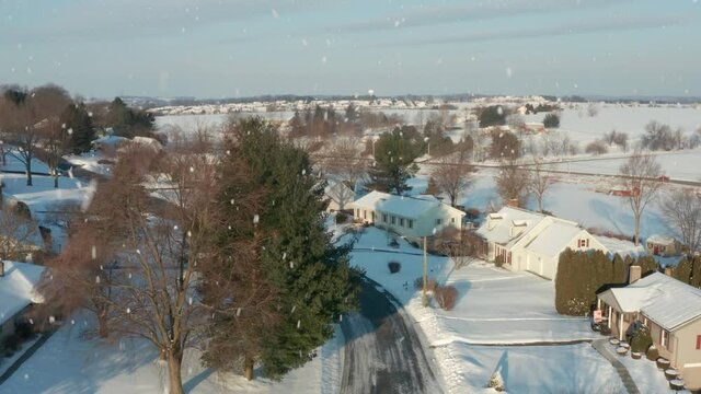 Snow scene. Aerial tracking shot through neighborhood housing development. Winter on sunny day in Pennsylvania, USA.
